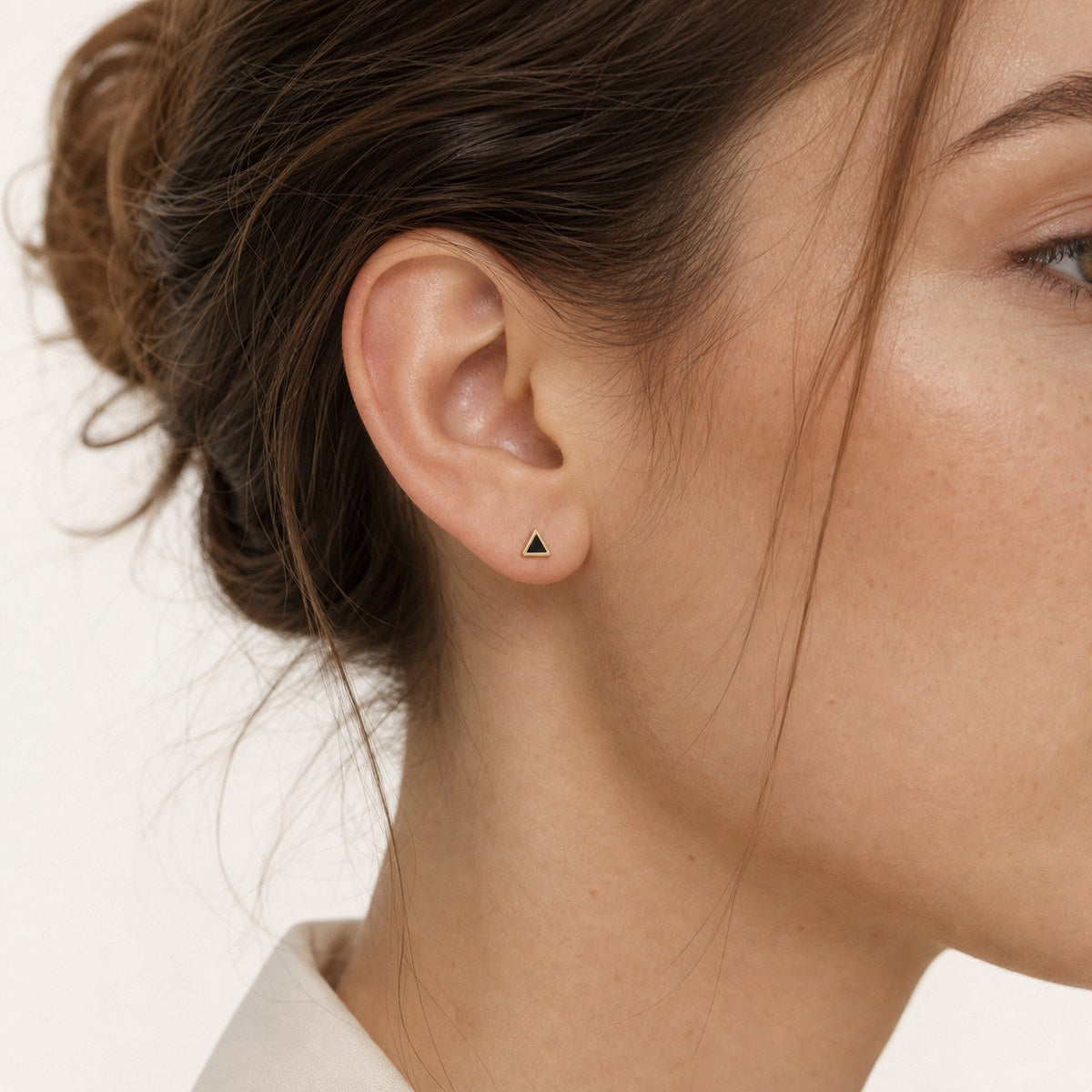 14K solid gold black triangle stud earrings worn on an ear