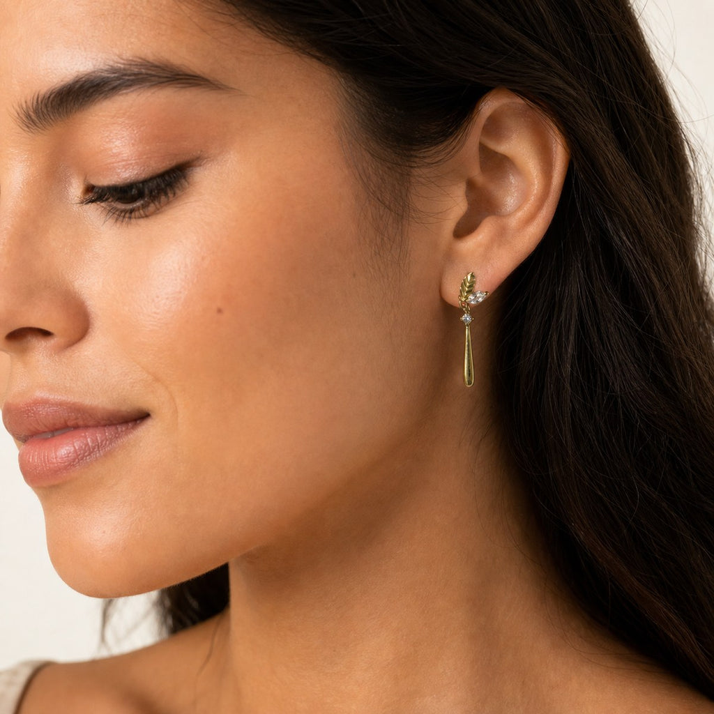 14K solid gold leaf teardrop drop stud earrings worn on an ear