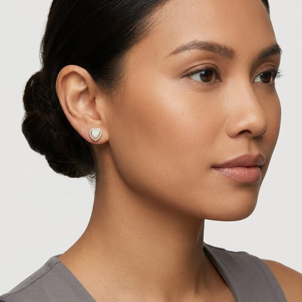 14K solid gold opal heart halo stud earrings worn on an ear