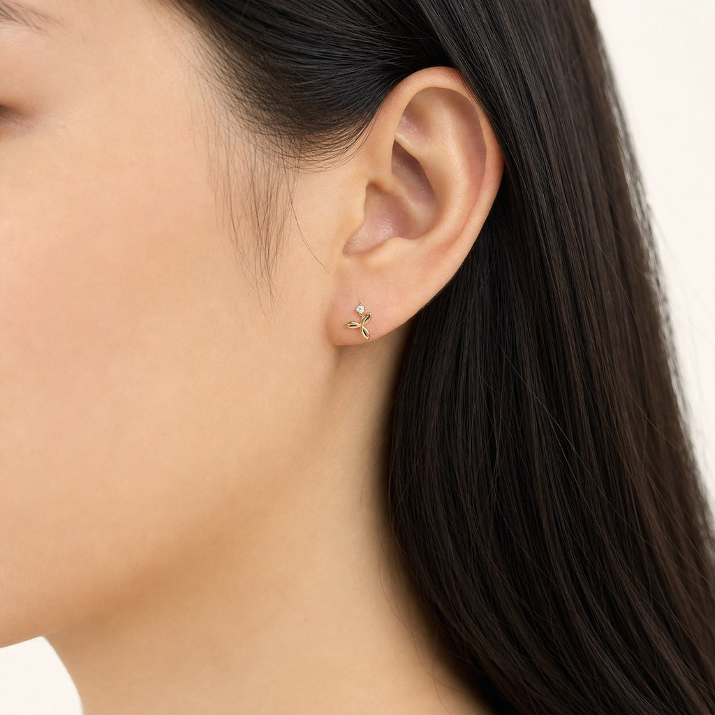 14K solid gold flower sprig stud earrings worn on an ear