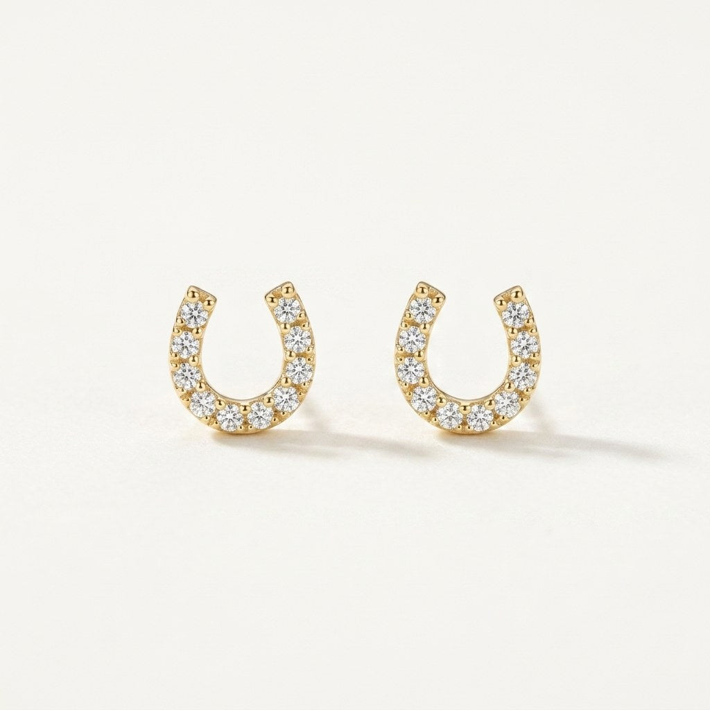 14K solid gold crystal horseshoe stud earrings on a warm ivory background