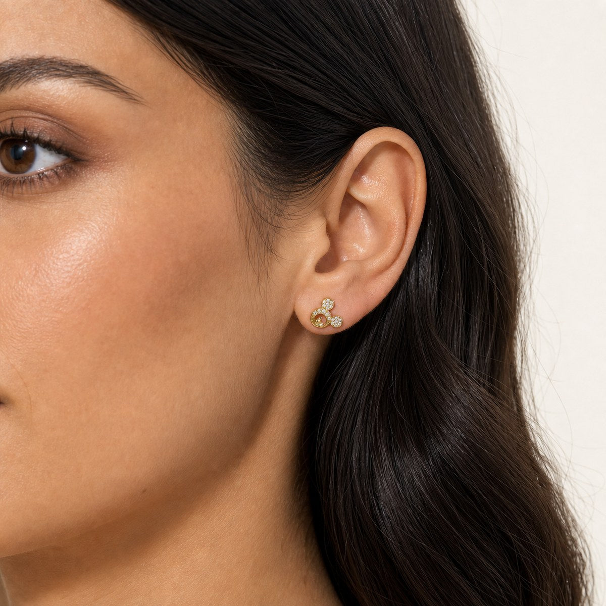 14K solid gold crystal bear paw stud earrings worn on an ear