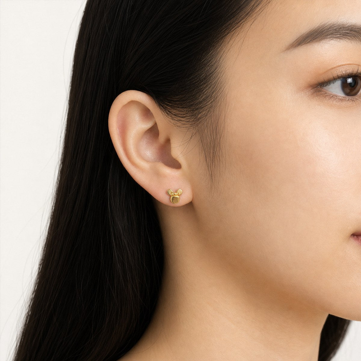 14K solid gold mouse face stud earrings worn on an ear