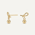 14K solid gold bow ball drop stud earrings on a warm ivory background