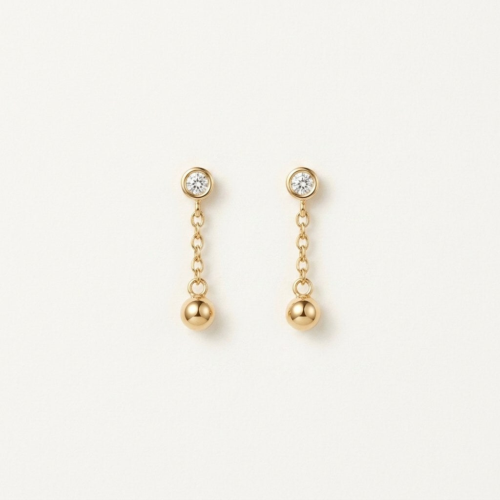 14K solid gold bezel ball chain drop earrings on a warm ivory background