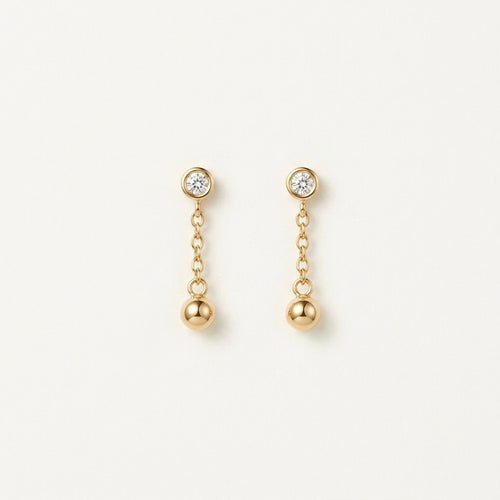14K solid gold bezel ball chain drop earrings on a warm ivory background