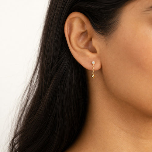 14K solid gold bezel ball chain drop earrings worn on an ear