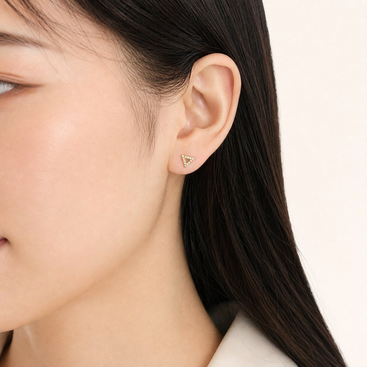 14K solid gold pearl triangle stud earrings worn on an ear