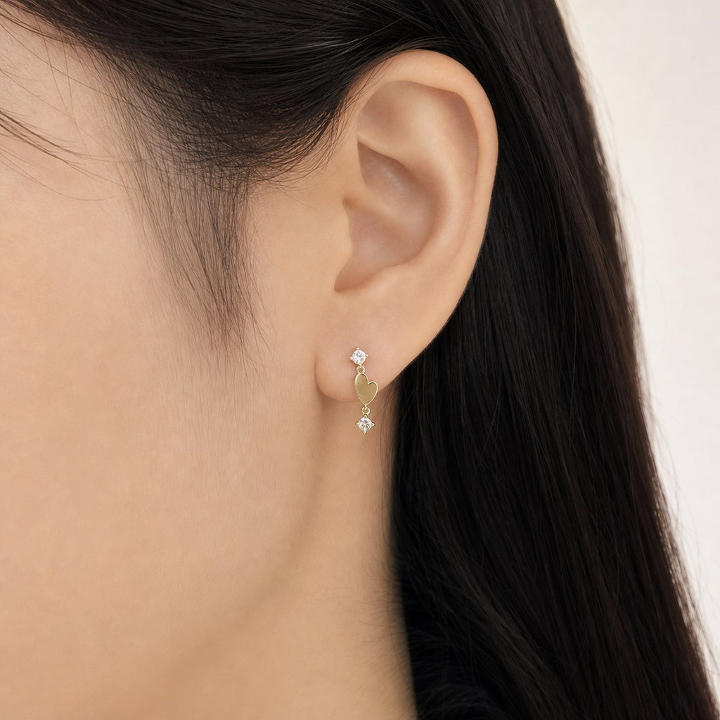 14K solid gold double heart drop stud earrings worn on an ear