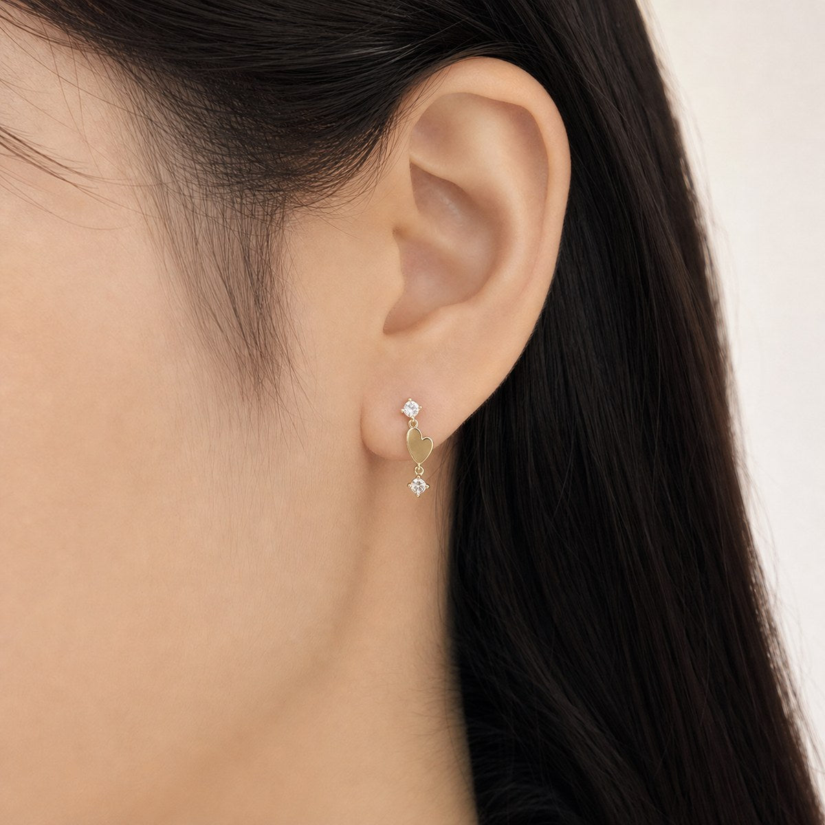 14K solid gold double heart drop stud earrings worn on an ear