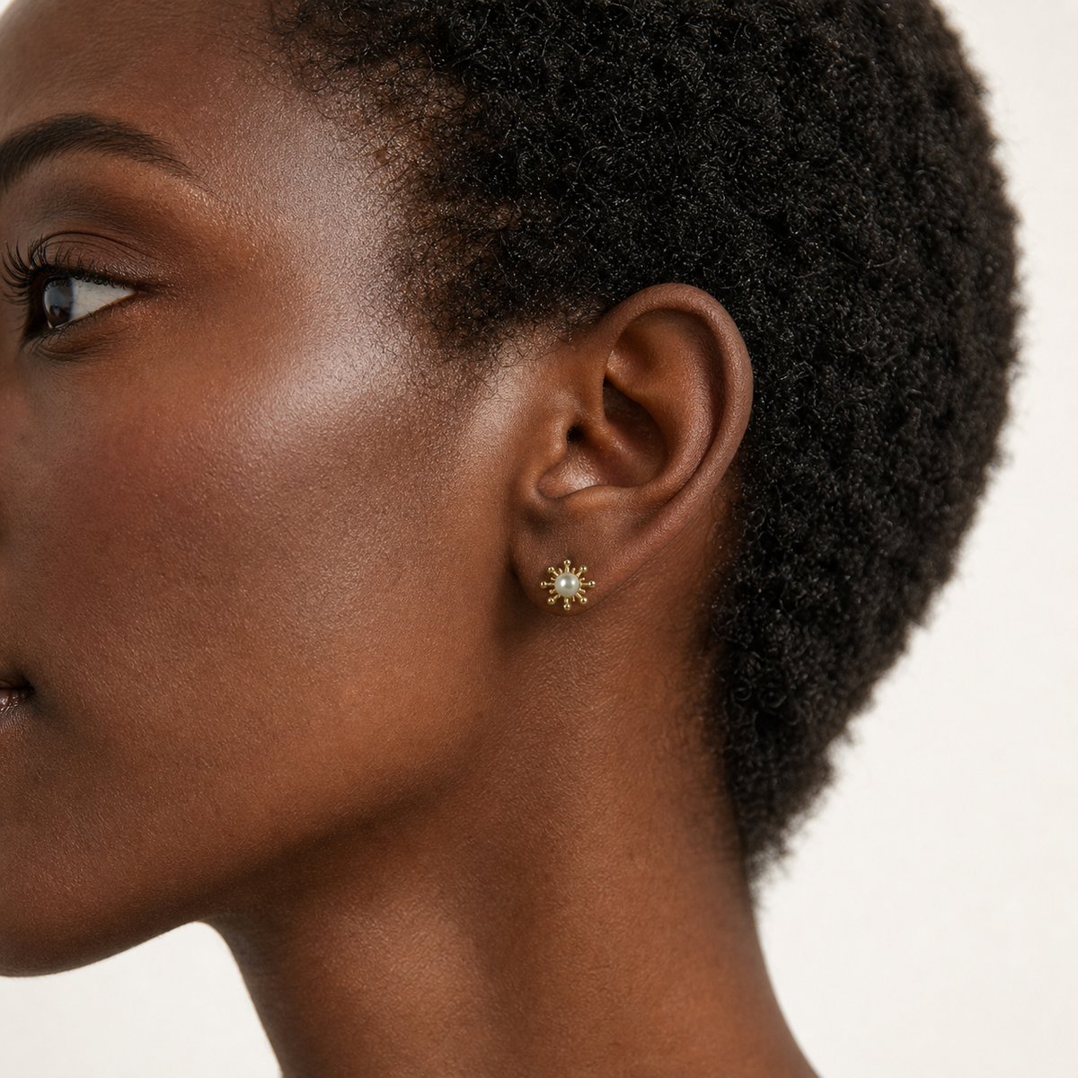 14K solid gold pearl sunburst stud earrings worn on an ear