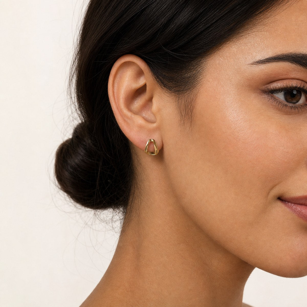 14K solid gold sculpted teardrop stud earrings worn on an ear