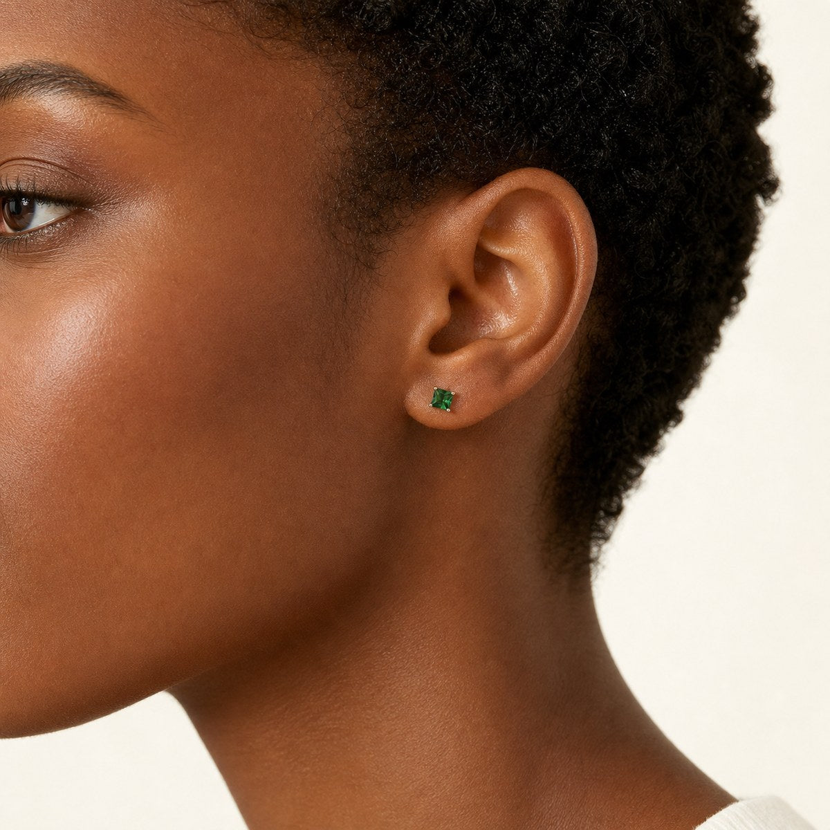 14K solid gold green princess cut stud earrings worn on an ear