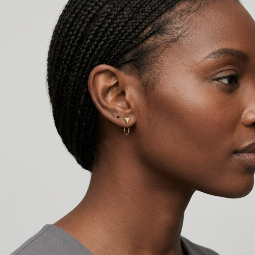 14K solid gold arrow hoop stud earrings worn on an ear