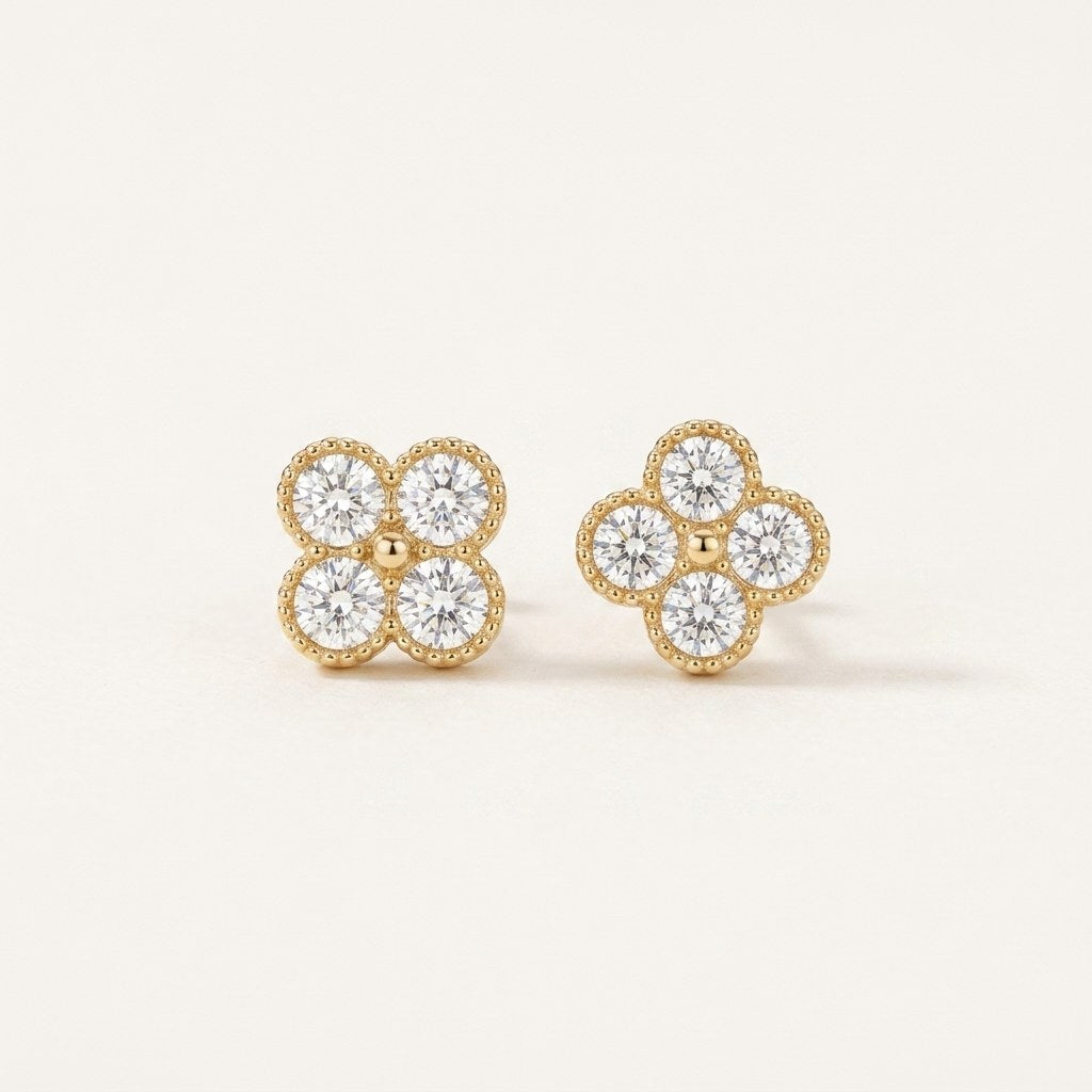 14K solid gold four leaf clover stud earrings on a warm ivory background
