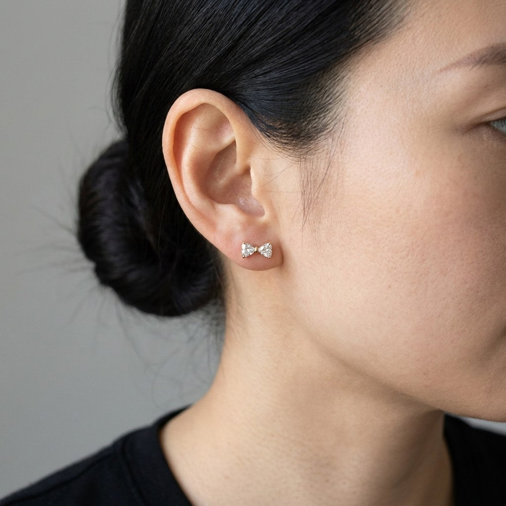 14K solid gold crystal ribbon bow stud earrings worn on an ear