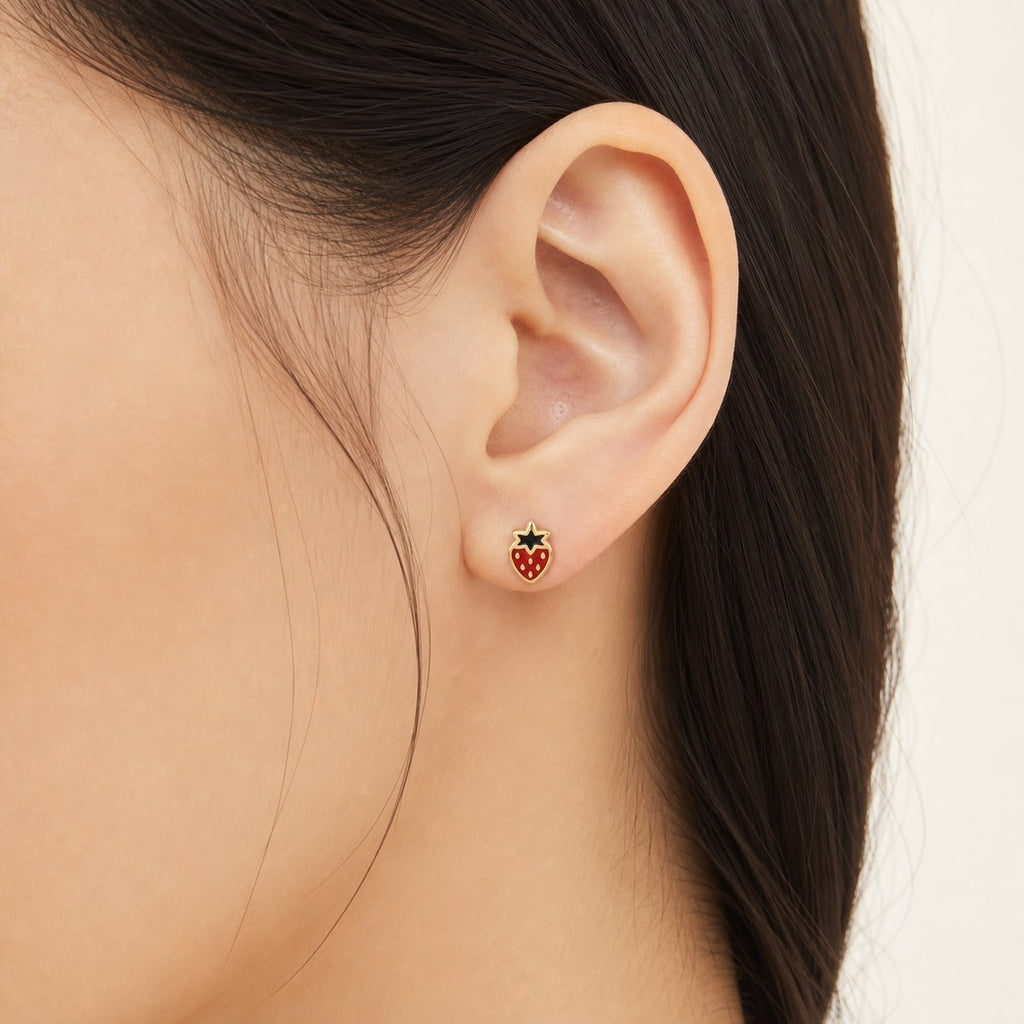 14K solid gold red strawberry stud earrings worn on an ear