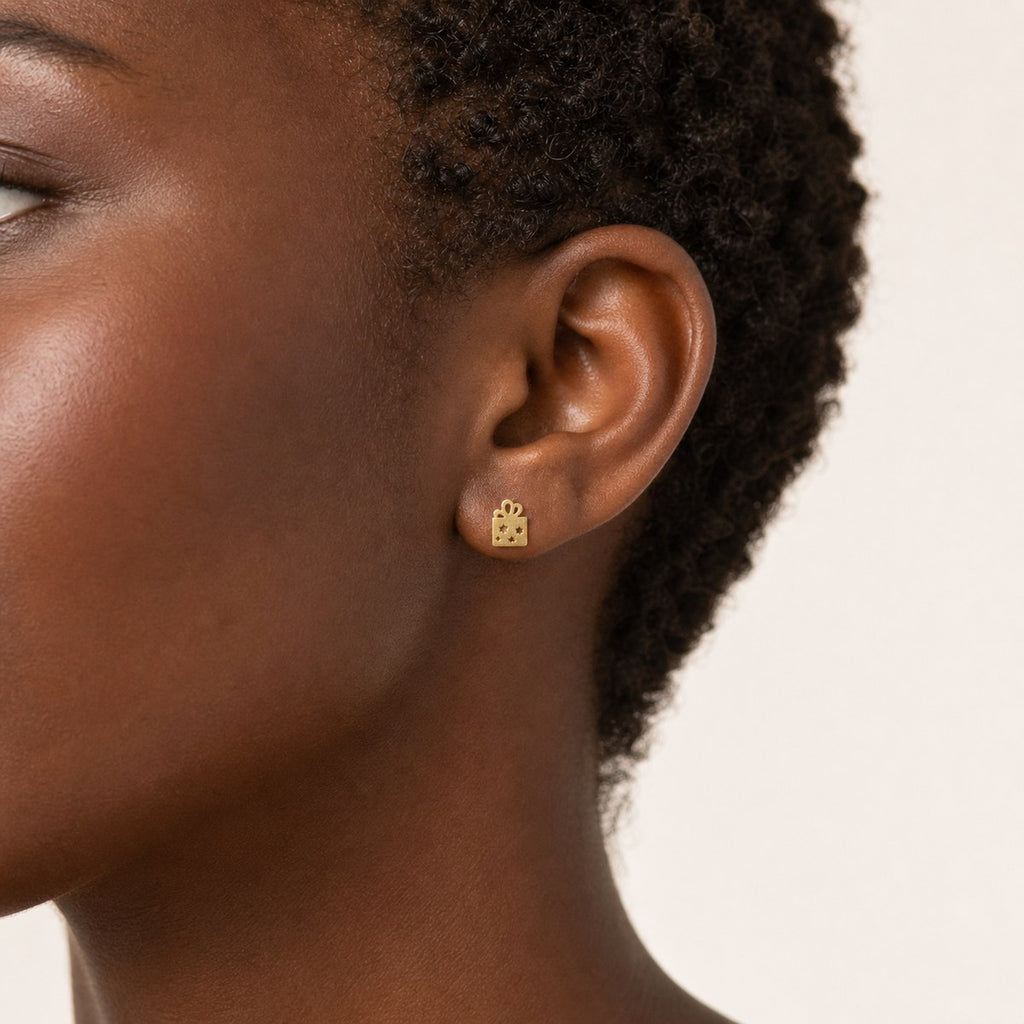14K solid gold star gift box stud earrings worn on an ear