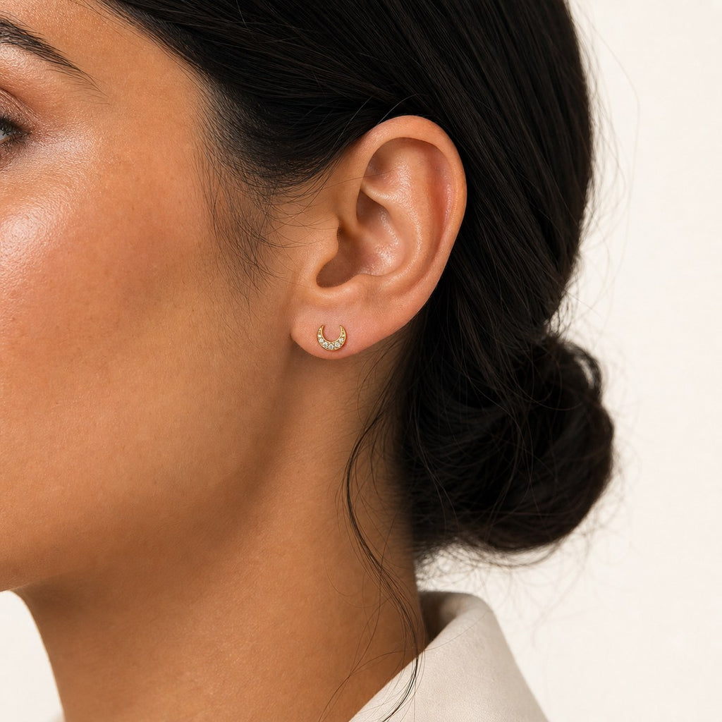 14K solid gold crescent crystal halo stud earrings worn on an ear