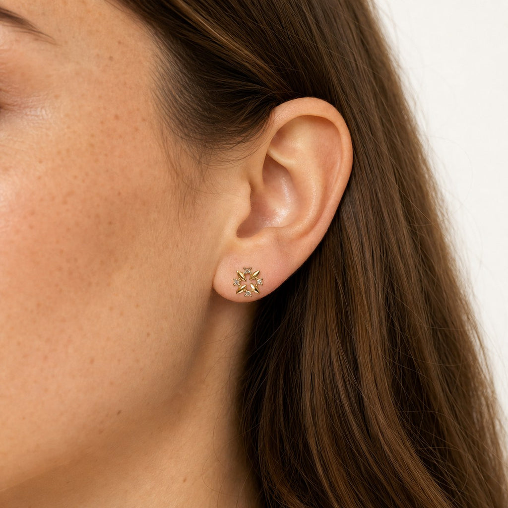 14K solid gold crystal pinwheel flower stud earrings worn on an ear