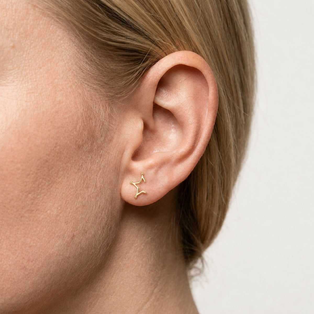 14K solid gold minimal constellation stud earrings worn on an ear