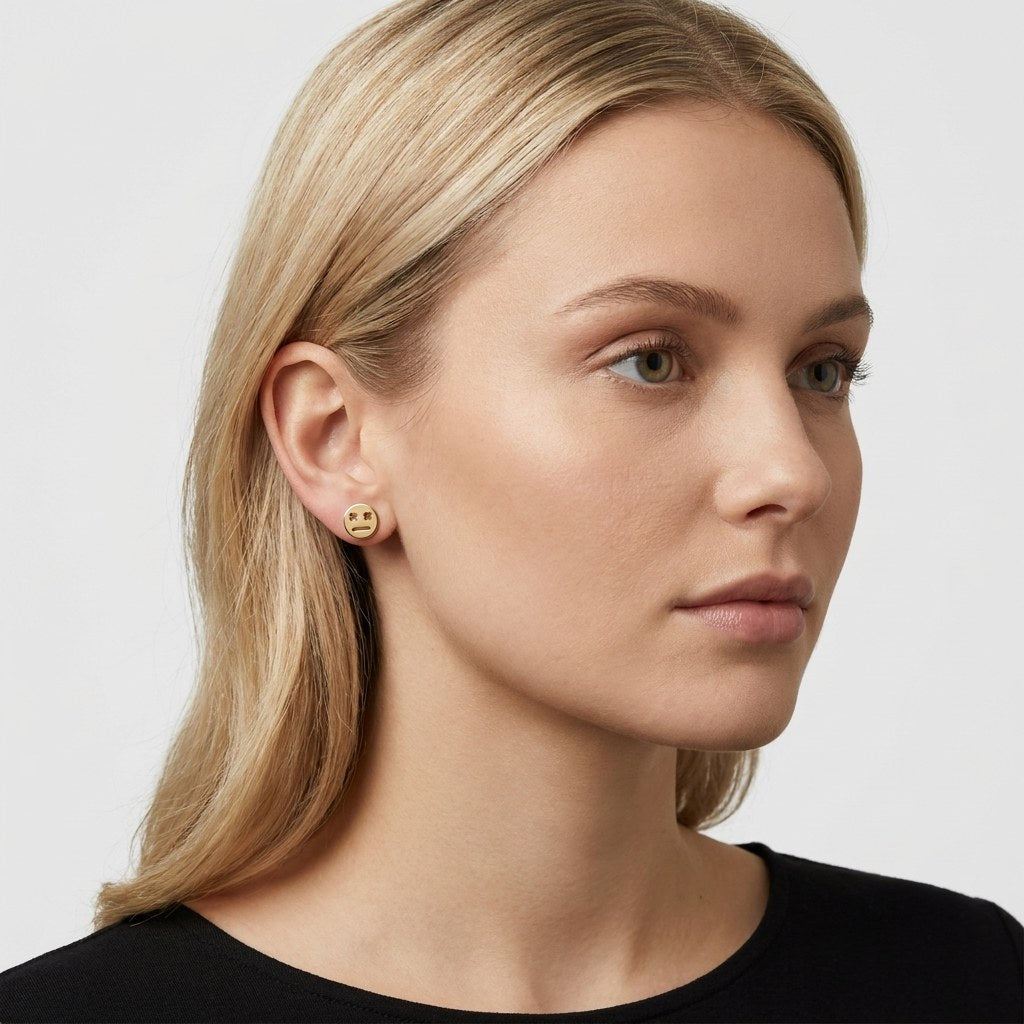 14K solid gold robot face stud earrings worn on an ear
