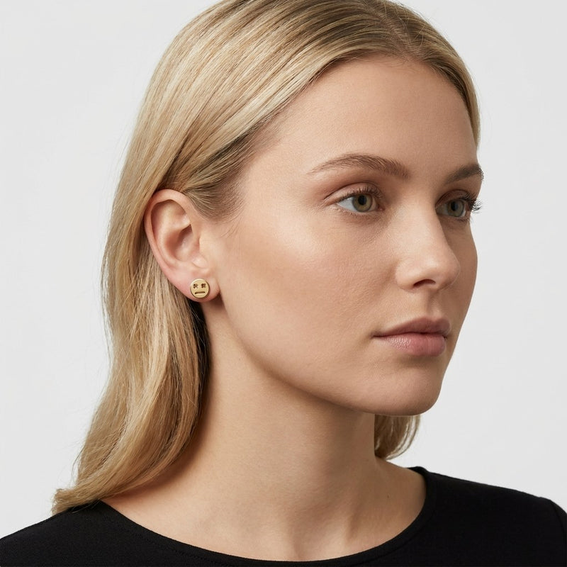 14K solid gold robot face stud earrings worn on an ear
