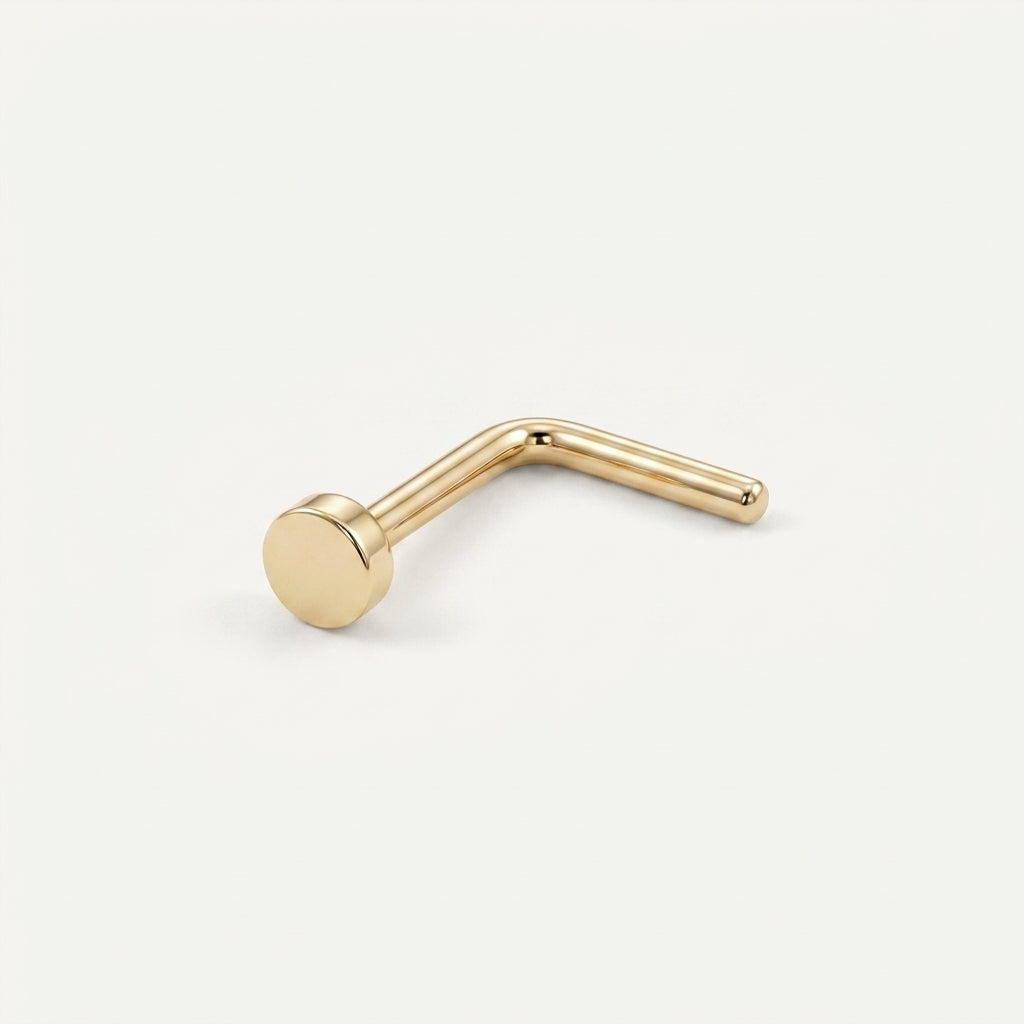 Solid Gold Disc Nose Stud in yellow gold on a warm ivory background