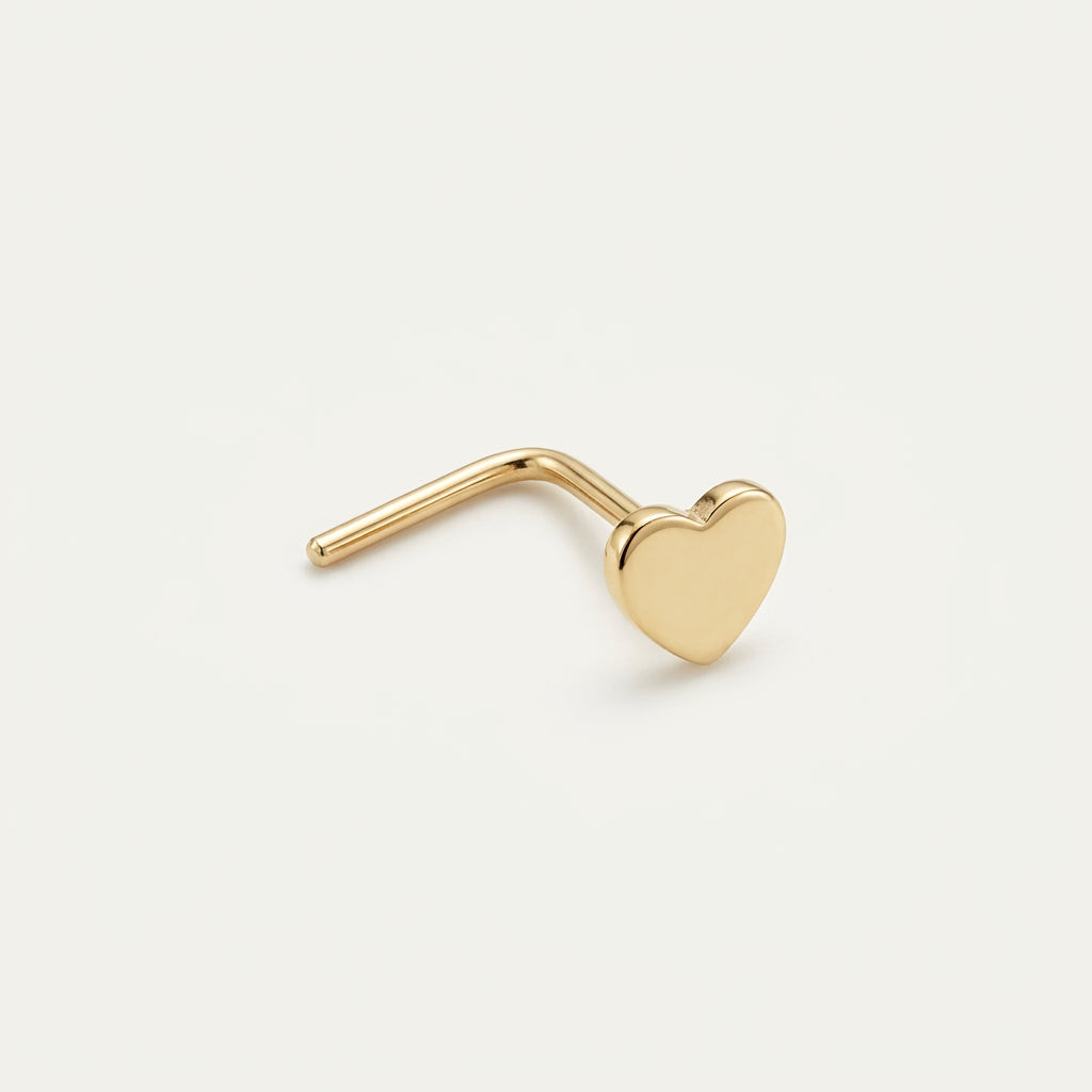 Solid Gold Heart Nose Stud in yellow gold on a warm ivory background