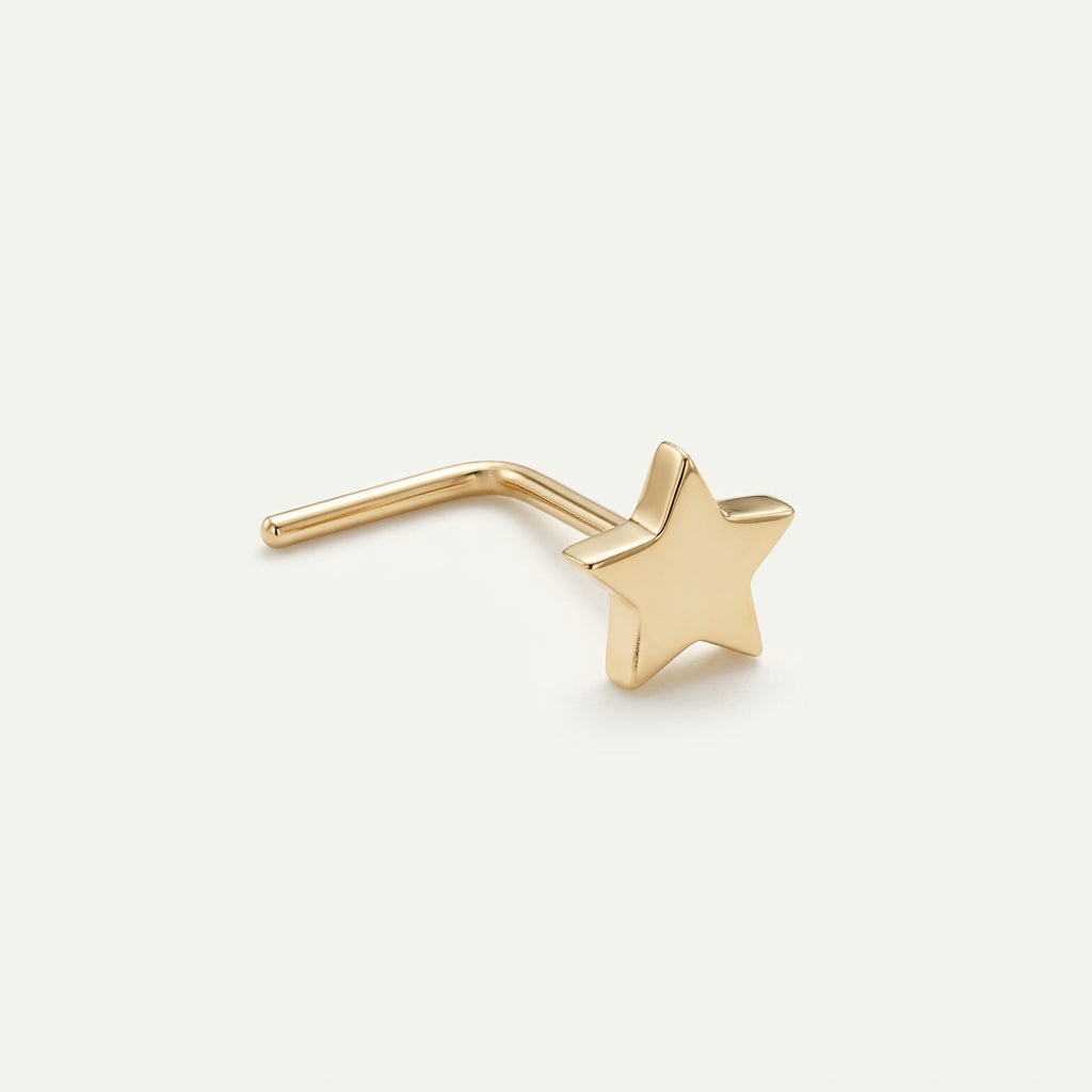 Solid Gold Star Nose Stud in yellow gold on a warm ivory background