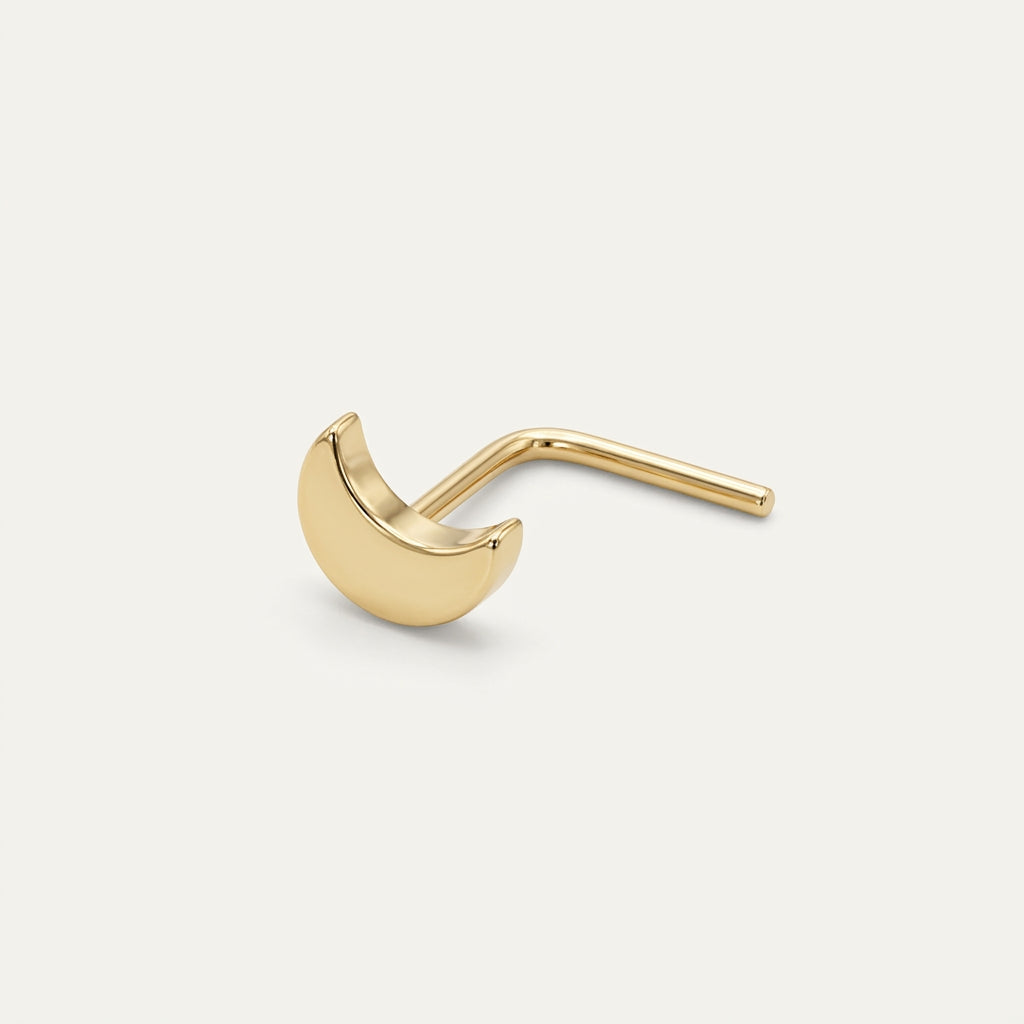 Solid Gold Crescent Moon Nose Stud in yellow gold on a warm ivory background
