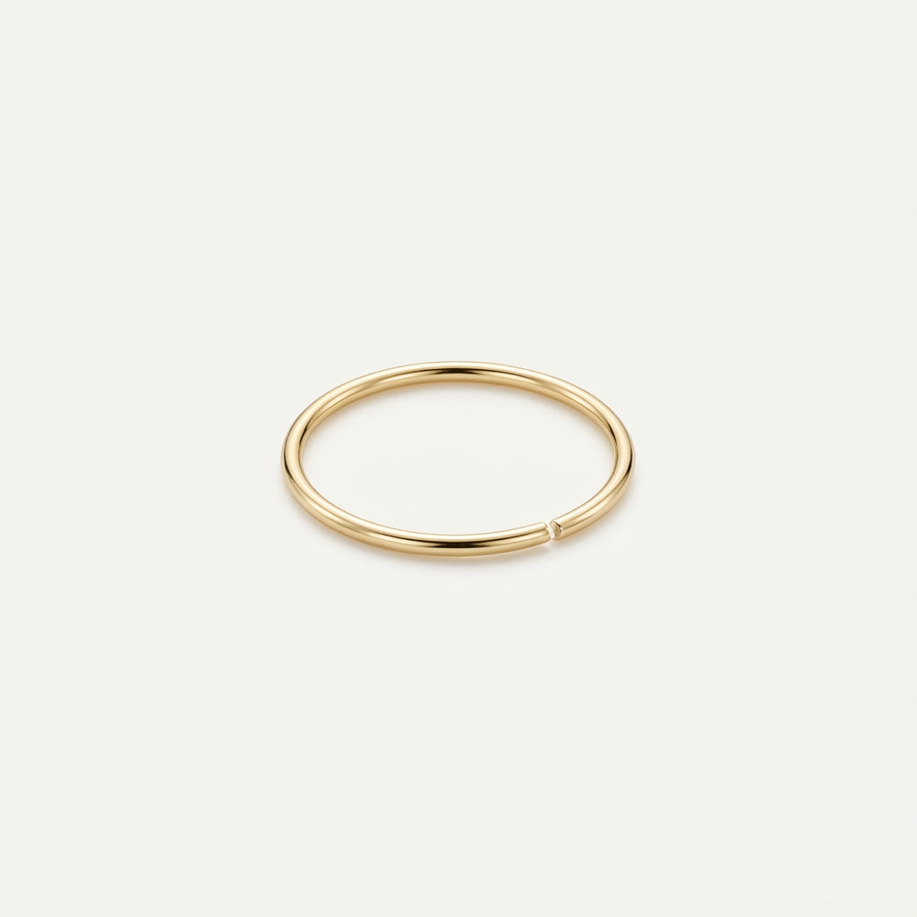 Solid Gold Seamless Nose Hoop in yellow gold on a warm ivory background
