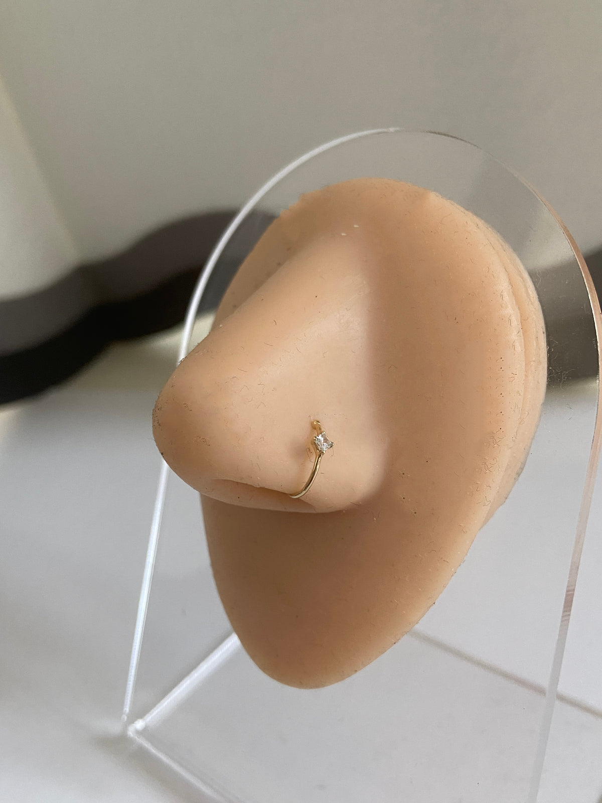 Actual product photo of Solid Gold Square Gemstone Nose Hoop on a display nose