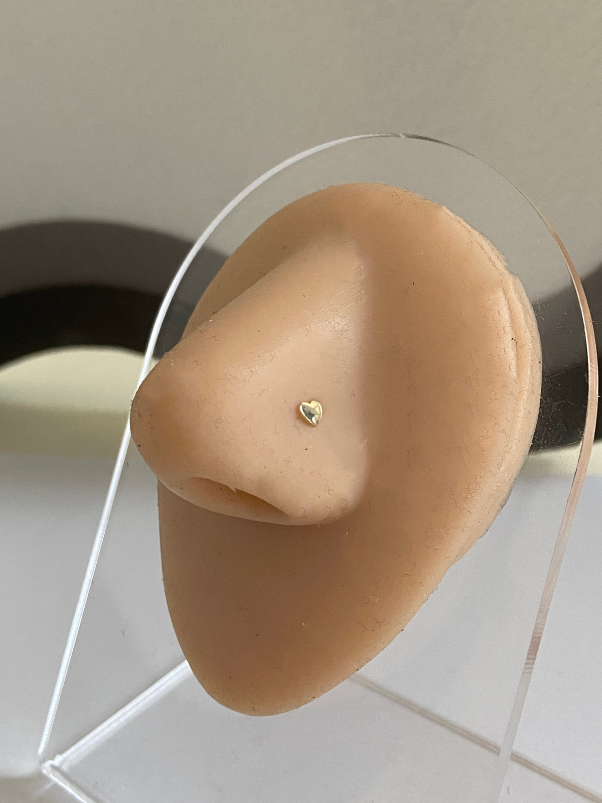 Actual product photo of Solid Gold Heart Nose Stud on a display nose