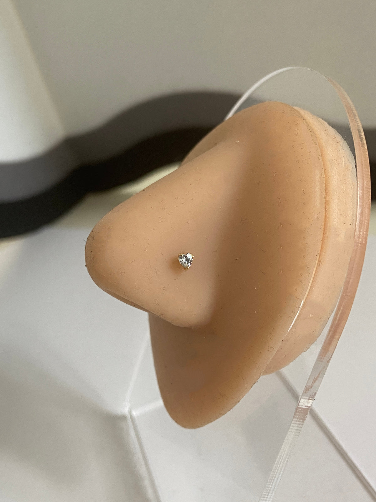 Actual product photo of Solid Gold Heart Gemstone Nose Stud on a display nose